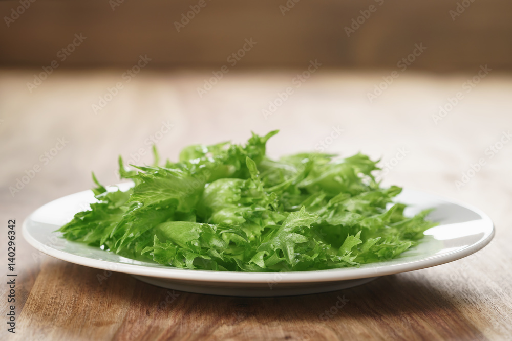green frillies lettuce on white plate on wooden table, closeup photo green frillies lettuce on white plate on wooden table, closeup photo
