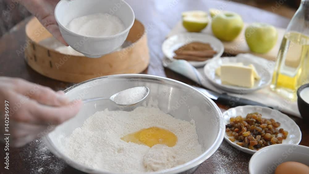 A man prepares a dough for baking buns and apple pie.
