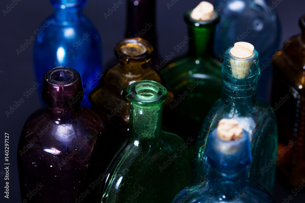 Old colourful bottles against a dark background Old colourful bottles against a dark background
