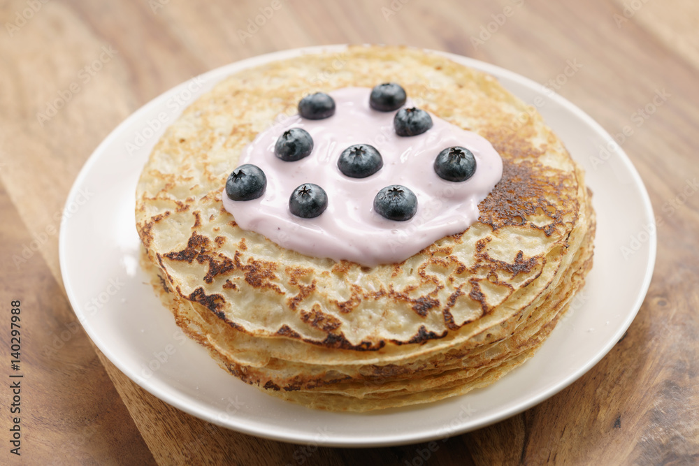 blini or crepes with yogurt and blueberries on wood table, sweet breakfast
