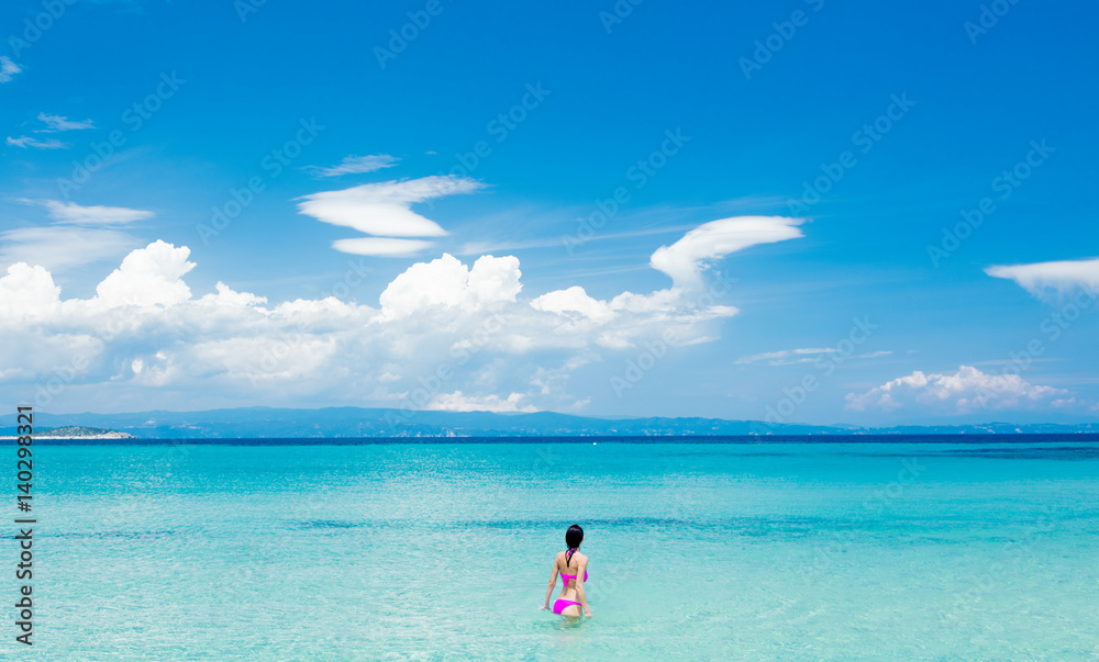 beautiful young woman standing in the wonderful clean sea in greece