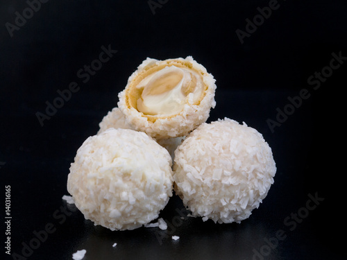 Raffaello white candy with coconut flakes on a black background photo