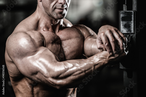 Handsome fit caucasian muscular man flexing his muscles in gym