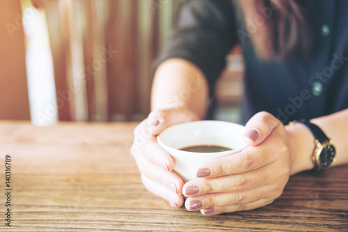 A woman holding a cup of coffee on wooden vintage table