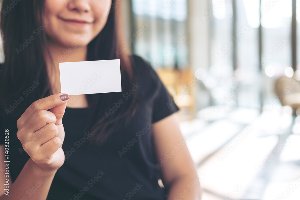 An image of a beautiful woman holding and showing empty business card in modern loft cafe An image of a beautiful woman holding and showing empty business card in modern loft cafe
