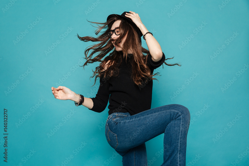 Pretty modern young woman in black hat dancing and whirling - obrazy, fototapety, plakaty 