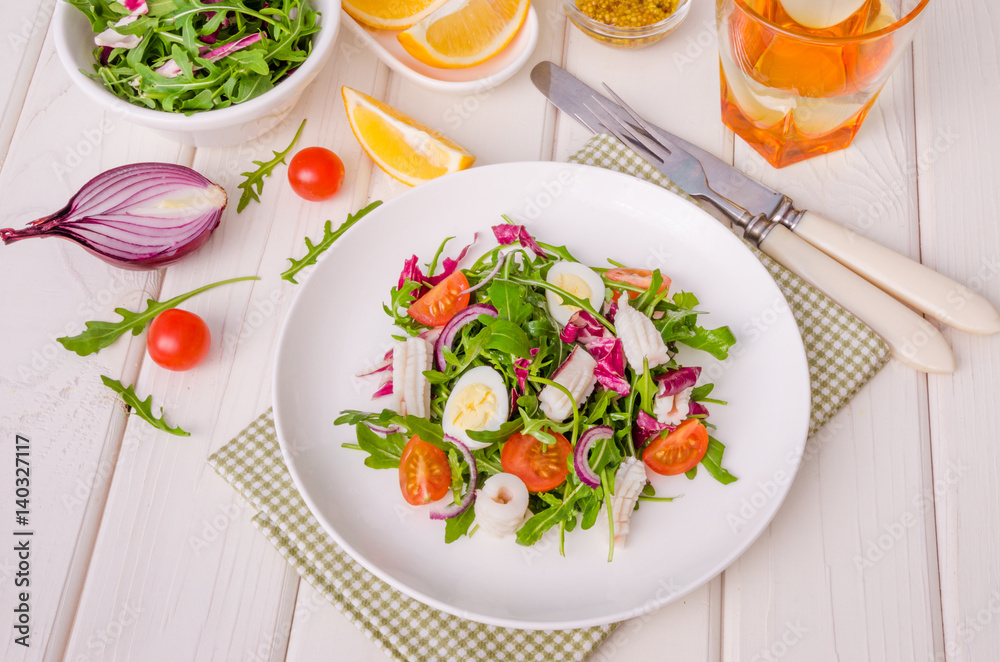 Salad with arugula, squid, cherry tomatoes, onion and quail eggs