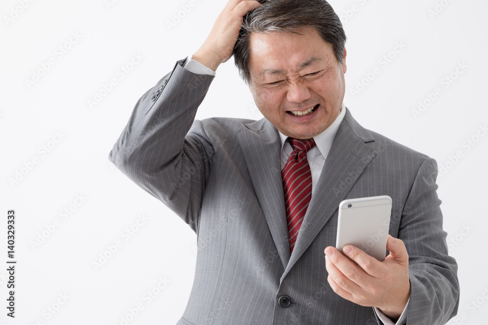 携帯電話を持つビジネスマン、頭をかく、頭を抱える、困る、中年男性 携帯電話を持つビジネスマン、頭をかく、頭を抱える、困る、中年男性