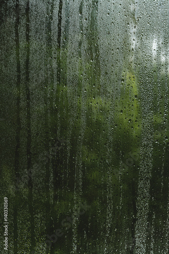condensation droplets in a window glass, green nature abstract background