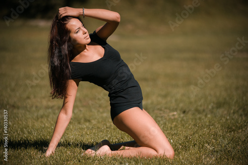 pretty girl performing fitness activities and stretching on the lawn © alipko