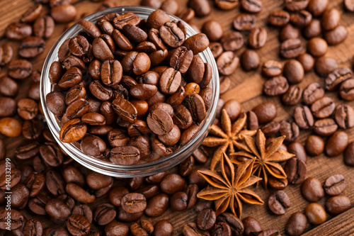 Coffee beans and cinnamon on a background of burlap. Roasted coffee beans background close up. Coffee beans pile from top with copy space for text. Seasoning. Spice. Cinnamon. Badian. Coffee house.