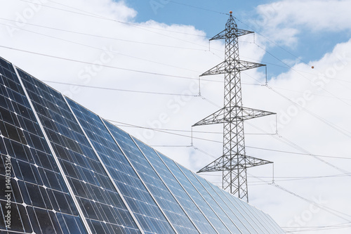 Solarzelle zur ökologischen Energiegewinnung und Strommasten als Energie Infrastruktur im Hintergrund