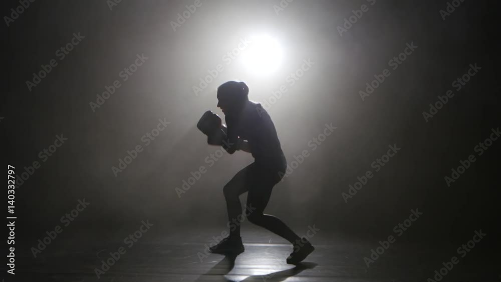 Champion kickboxer smoke evades counter punches. Silhouette. Black background . Side view Champion kickboxer smoke evades counter punches. Silhouette. Black background . Side view