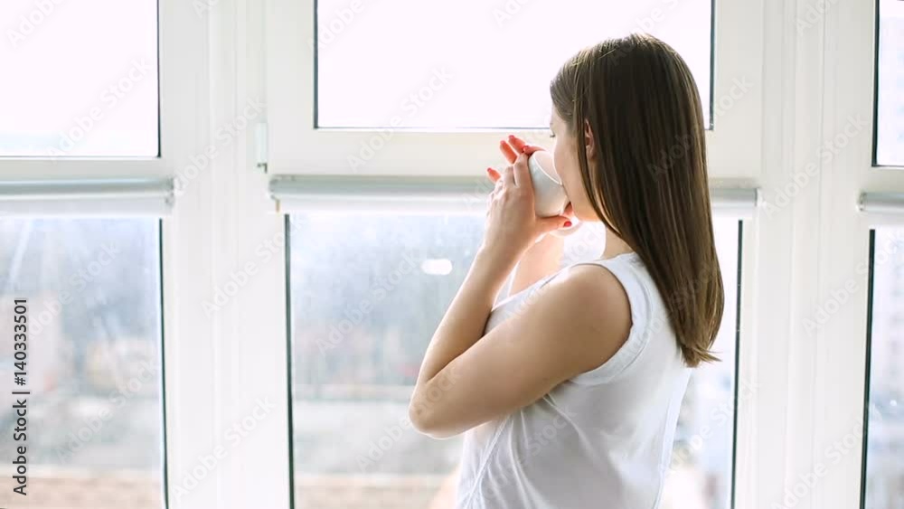 Woman waking up and standing by the window Woman waking up and standing by the window