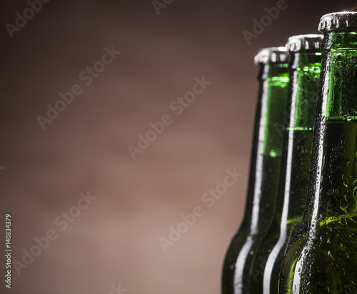 Glass bottles of beer on brown background