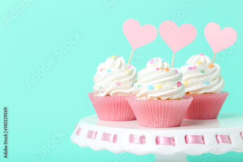 Tasty cupcakes on cake stand on green background