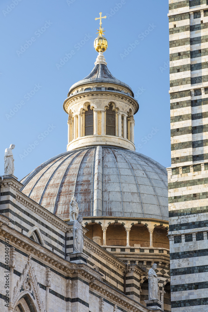 Belfry with golden cross of cathedral in Tuscany in Italy