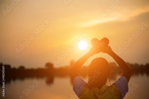 A woman holding a sunset heart