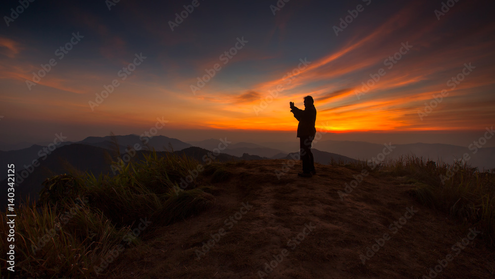 Silhouette of a man taking picture in the sunset
