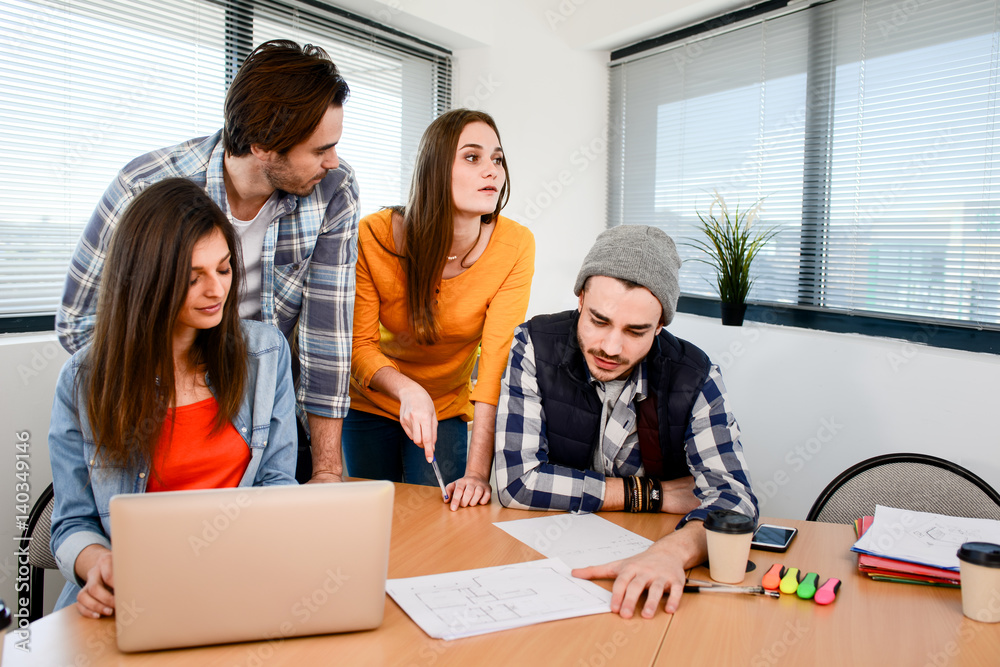 Obraz premium group of four young business people man and woman in casual wear working in a creative business startup company office
