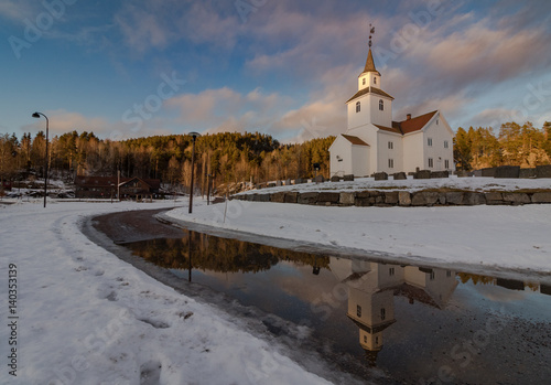 Church reflected in water, winter, snow and blue sky in Iveland Norway photo
