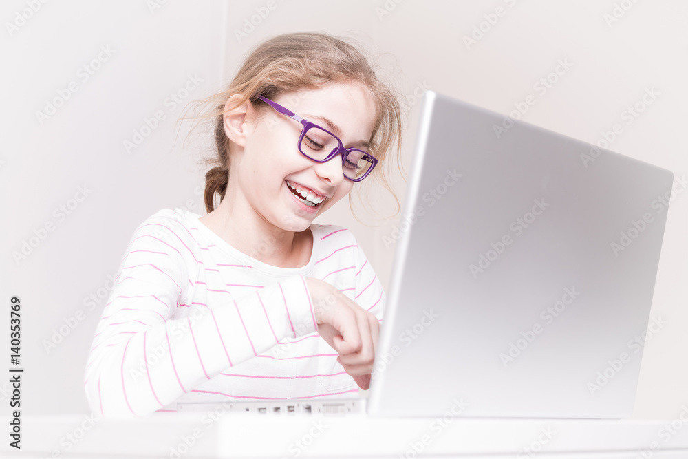 Happy smiling child girl (kid) using laptop computer Happy smiling child girl (kid) using laptop computer