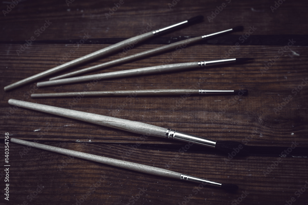 Different paint brushes in wooden background