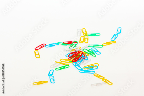 Many colored clips are in the shape of a little man. Stationery on a light background. Small office items. Blur effect. photo