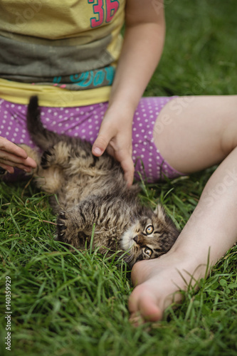 Little girl playing with her little kitten in the garden.