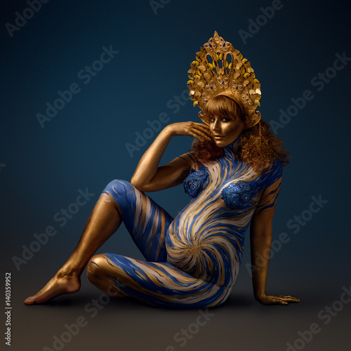 Fotografie Fashionable redhead pregnant woman with kokoshnik and abstract body art in shade