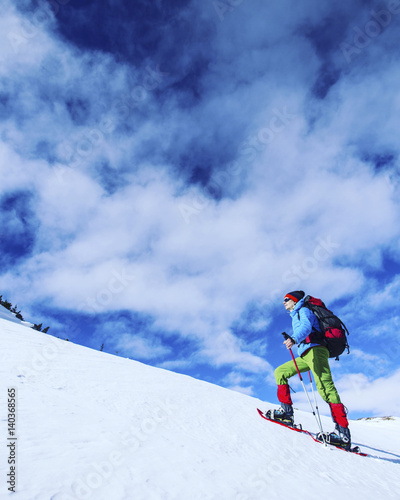 Winter hiking in the mountains on snowshoes with a backpack and tent.