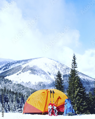 Winter hiking in the mountains on snowshoes with a backpack and tent.