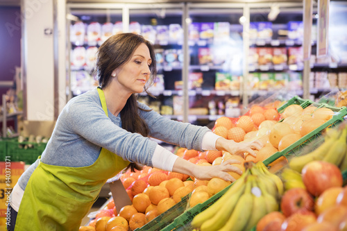 Saleswoman Arranging Oranges In Supermarket