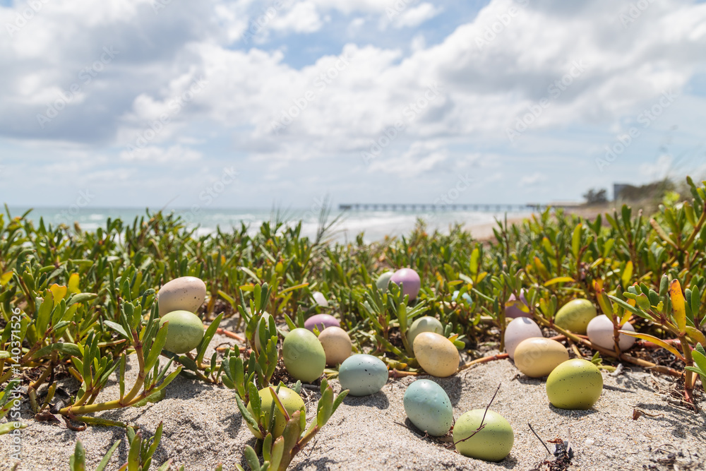 Obraz premium Colorful Easter eggs on the sandy tropical beach background.