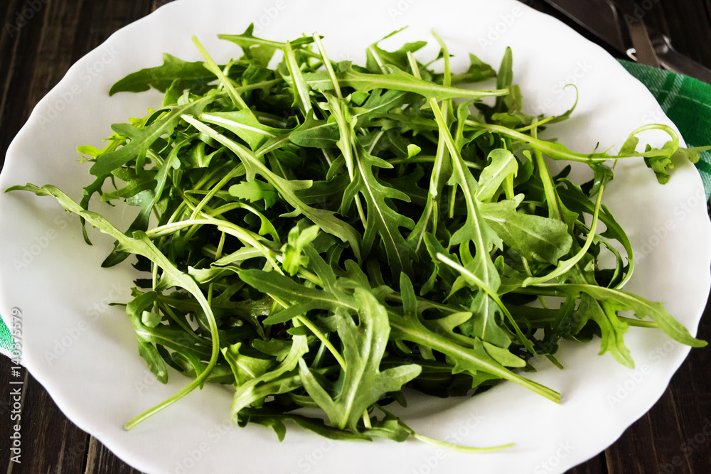 Fresh juicy arugula on a white plate Fresh juicy arugula on a white plate