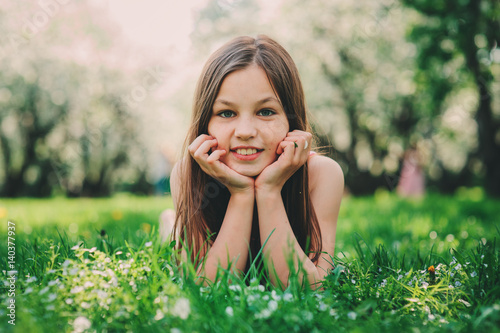 spring closeup outdoor portrait of adorable 11 years old preteen kid girl. Spending spring holidays in beautiful blooming cherry garden