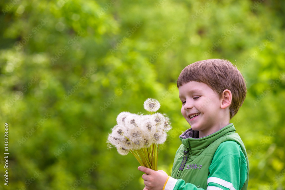 Funny cute kid boy having fun with dandelion flower on warm and sunny summer day. Kid blowing on flower, active outdoors leisure with children Funny cute kid boy having fun with dandelion flower on warm and sunny summer day. Kid blowing on flower, active outdoors leisure with children