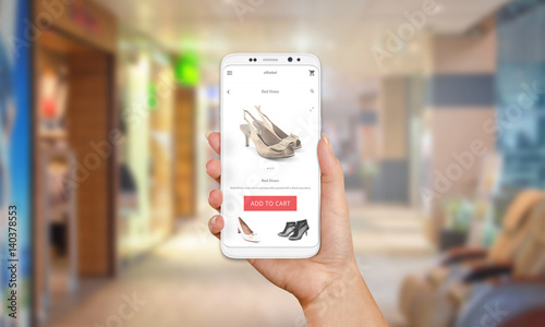 Online shop on mobile phone display. Modern white smart phone with round edges in girl hand. Shopping mall in background.