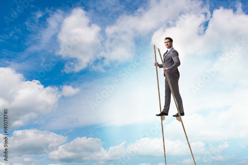 Businessman walking on stilts - standing out from the crowd photo