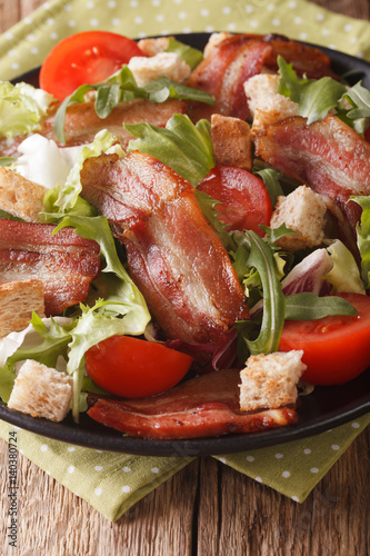 Spicy salad of bacon, tomato, croutons and lettuce close-up on a plate. vertical