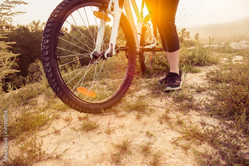 Girl on mountain bike rides on the trail on a beautiful sunrise. Bicycle wheel closeup