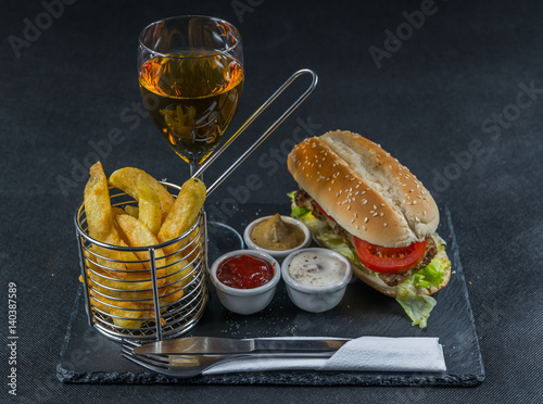 crusty white bread with sesame seeds, flavored with smoky ribsteak bbq, barbeque sauce, lettuce, tomato, three sauces, chips in a metal basket, white wine photo