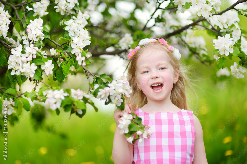 Adorable little girl in blooming apple tree garden on beautiful spring day Adorable little girl in blooming apple tree garden on beautiful spring day