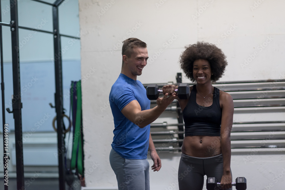 Obraz premium black woman doing bicep curls with fitness trainer