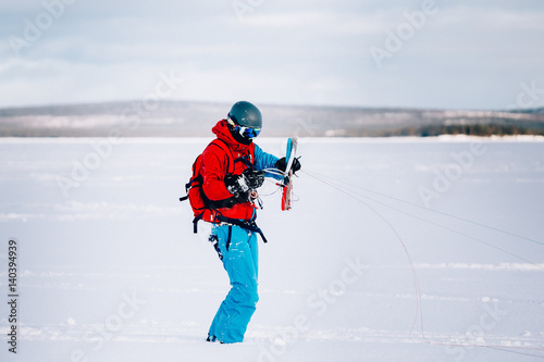 Snowkiting. A snowboarder athlete collects packs on a kite rink over a frozen lake. The Kola Peninsula. Kitesurfing. Snowkite.