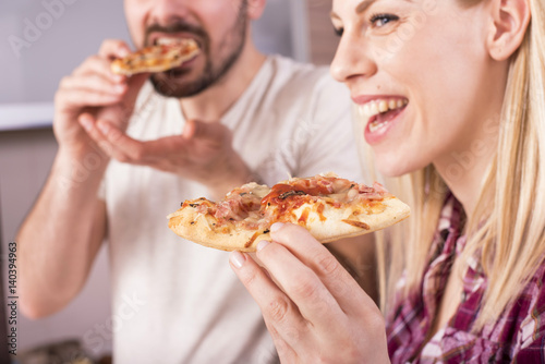 Couple having fun in the kitchen while making and eating pizza
