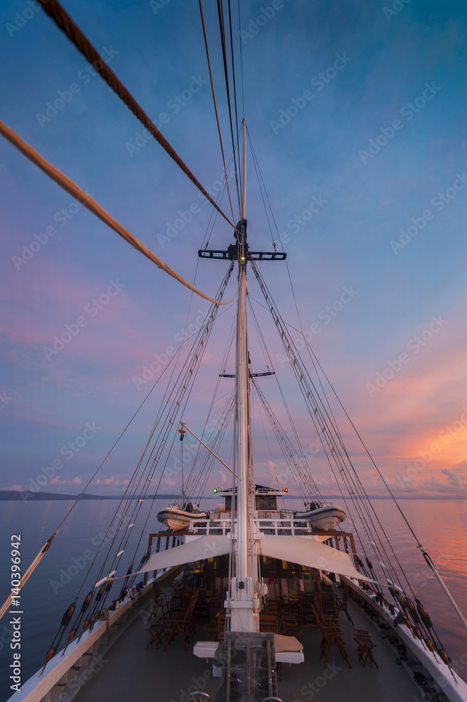 Indonesian Sunset from a Schooner Sailboat. Sailing through the Raja Ampat archipelago on a traditional phinisi schooner during a glorious sunset. Indonesian Sunset from a Schooner Sailboat. Sailing through the Raja Ampat archipelago on a traditional phinisi schooner during a glorious sunset.