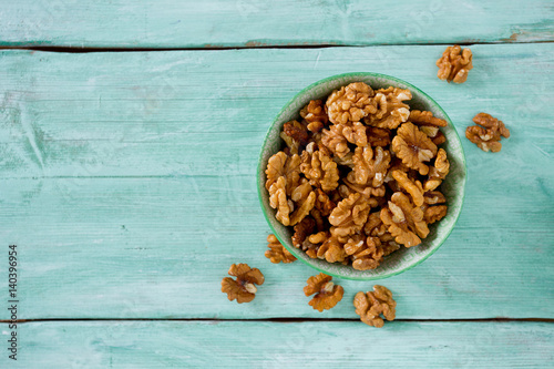 walnuts in a bowl on turquoise surface photo