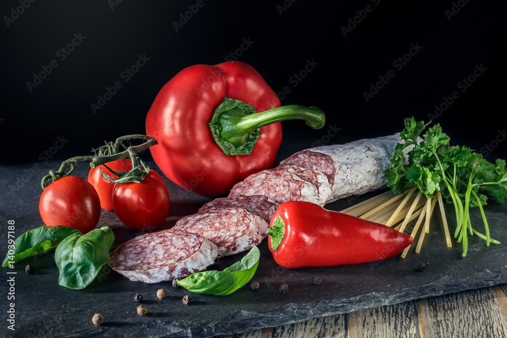 Salami with red paprika, tomatos and pepper on the slate board Salami with red paprika, tomatos and pepper on the slate board
