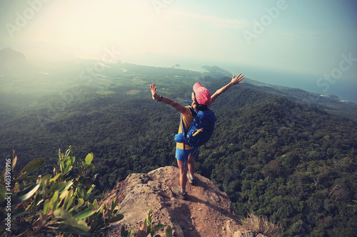 successful woman hiker open arms hiking on mountain peak
